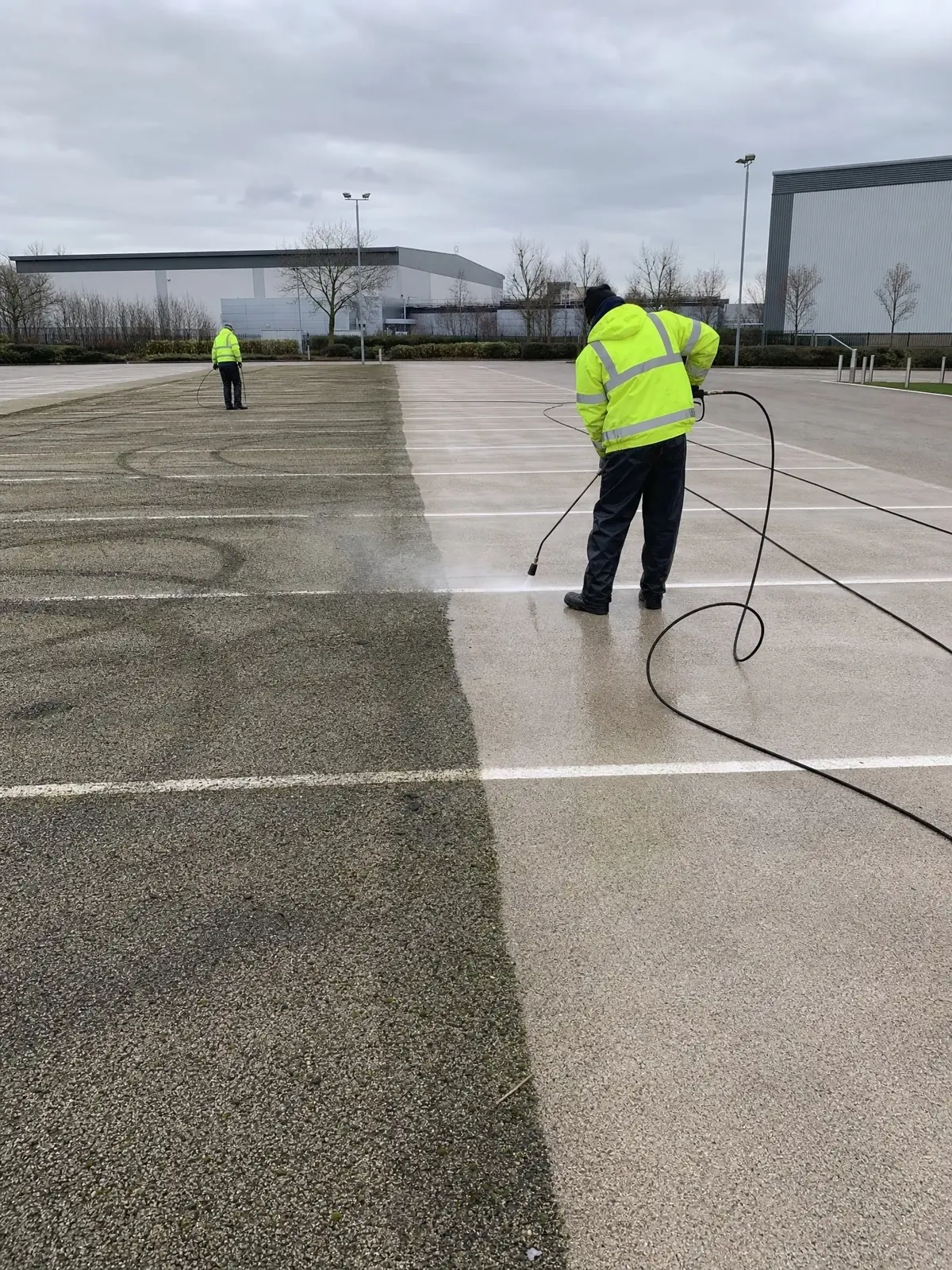 A large tarmac car park half pressure-washed, grimy against clean surface